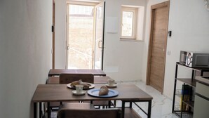 Un comedor con una mesa y sillas de madera, un ventanal pequeño y una puerta.