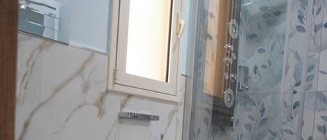 A bathroom with two toilets, a sink, and a glass-enclosed shower area.