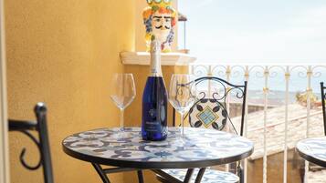 Una mesa con una botella de Prosecco y dos copas, una estatua decorativa y un mantel estampado.