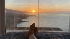 A balcony with a view of the ocean and a sunset.