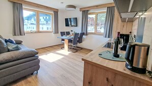 Eine moderne Küche mit Holzausstattung, ein Essbereich mit Tisch und Stühlen sowie ein Sofa im Wohnbereich.