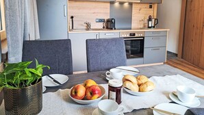 Eine kleine Küchenzeile mit grauen Schränken, einem eingebauten Backofen und einer Kaffeemaschine.