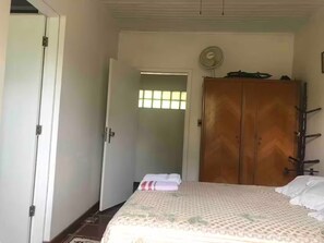 Un dormitorio con cama, armario, puerta y ventana.