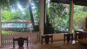 A covered outdoor dining area with wooden tables and chairs, surrounded by lush greenery and a white fence. - Charming place near SP (Caioçara Jarinu)