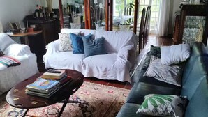 A living room with a white sofa, a black sofa, a coffee table, and a patterned rug. There are multiple mirrors and a chandelier. - Charming place near SP (Caioçara Jarinu)