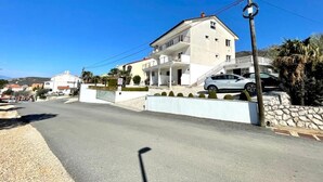 Un immeuble de deux étages doté d’un balcon, d’une allée et d’une voiture garée.