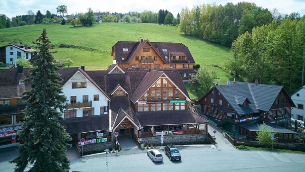 A traditional chalet-style building with a prominent wooden facade, multiple windows, and a sloped roof. - Beautiful apartment for 4 people with WIFI and TV (Jilemnice)