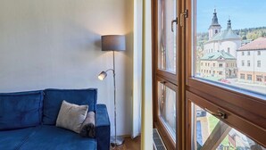 A room with a blue sofa, a floor lamp, and a window with a view of buildings. - Beautiful apartment for 4 people with WIFI and TV (Jilemnice)