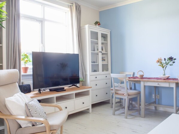 Un salon comprenant un téléviseur, un meuble, une table à manger et des chaises.