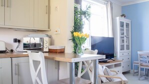 A modern kitchen with white cabinets, a wooden countertop, a toaster, a TV, and a vase with yellow flowers. - Stunning private villa for 6 people with WIFI and TV (Isle Of Skye)