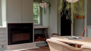 Una habitación acogedora con chimenea, muebles de mimbre y plantas colgantes.