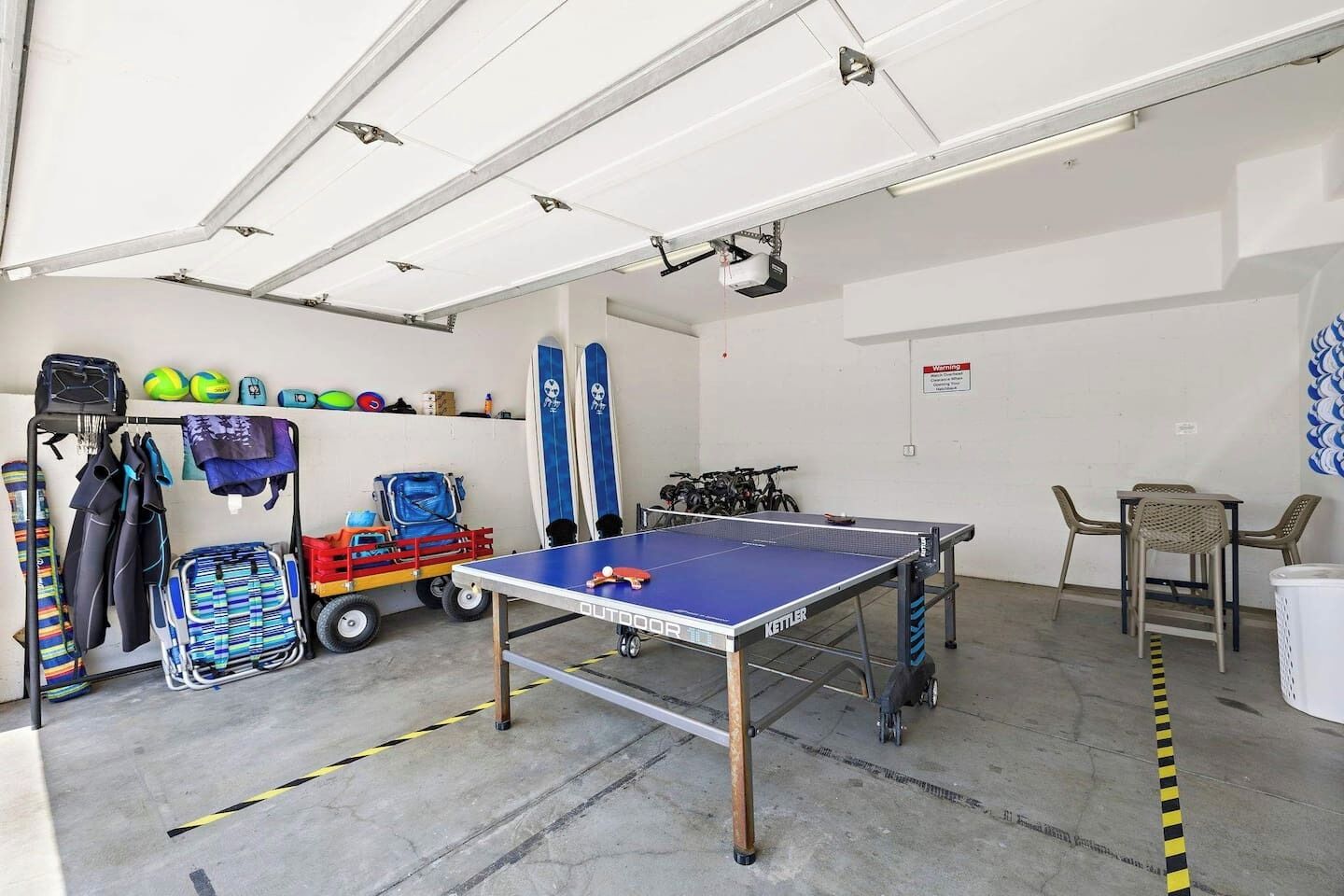 A room with a ping pong table, a bicycle, and various sports equipment.