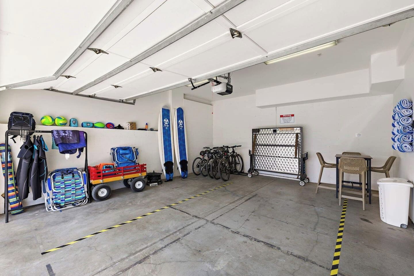 Eine Garage mit Betonboden, Fahrrädern, einem Kinderwagen und verschiedenen Sportgeräten.