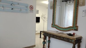 A room with a wooden console table, a mirror with a gold frame, and a wall-mounted light fixture.