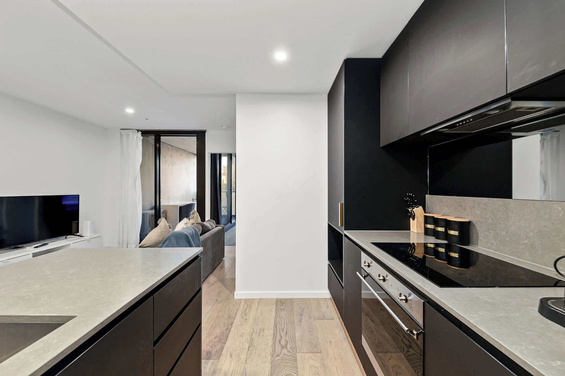 A modern kitchen with a central island, a built-in oven, and a dining area with a sofa.