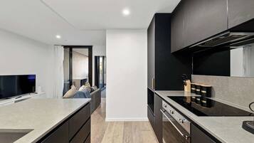 A modern kitchen with a central island, a built-in oven, and a dining area with a sofa.