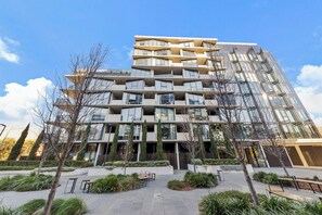 A multi-story residential building with balconies, a landscaped courtyard, and a modern architectural design.