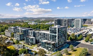 A modern urban area with high-rise buildings, a parking lot, and surrounding greenery. - Stylish Apartment in Canberra CBD (Reid)