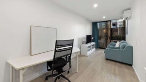 En moderne stue med et skrivebord, en blå sofa og et fjernsyn.