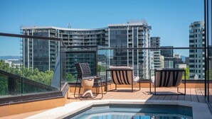 Une terrasse sur le toit avec une piscine, deux chaises et une table.