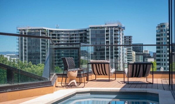A rooftop terrace with a pool, two chairs, and a table. - Stylish Apartment in Canberra CBD (Reid)