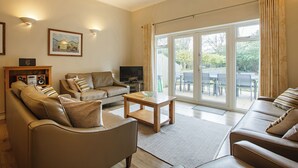 A spacious living room with a sofa set, a coffee table, and a television.