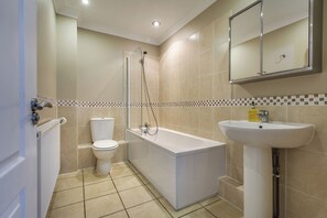 Une salle de bain moderne équipée d’une baignoire, de toilettes et d’un lavabo.