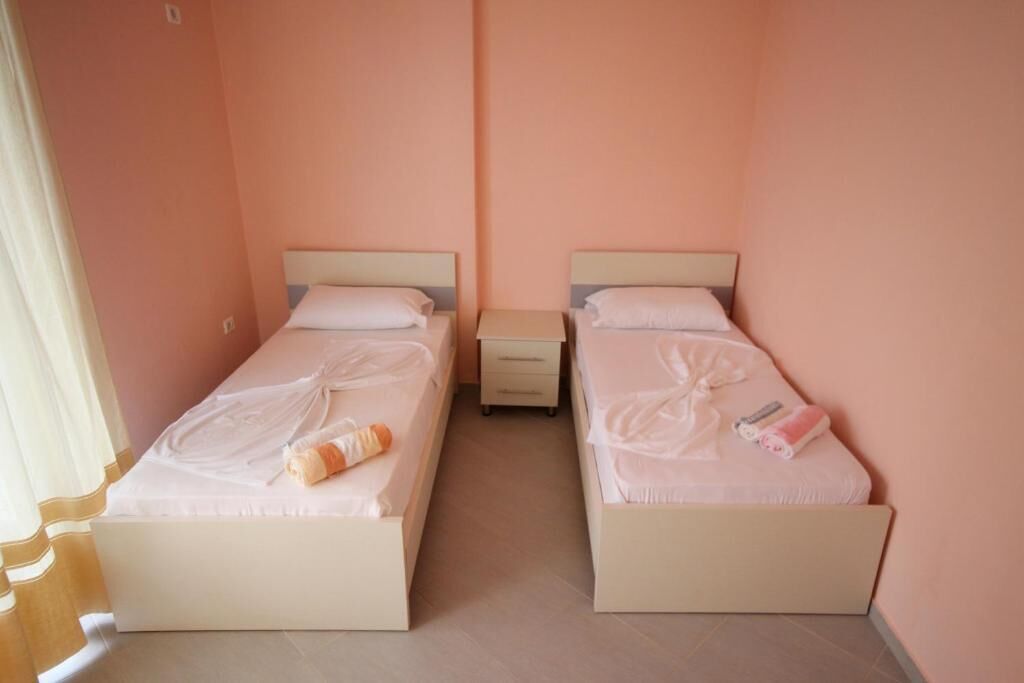 A room with two beds, each with a pillow and a small bedside table.