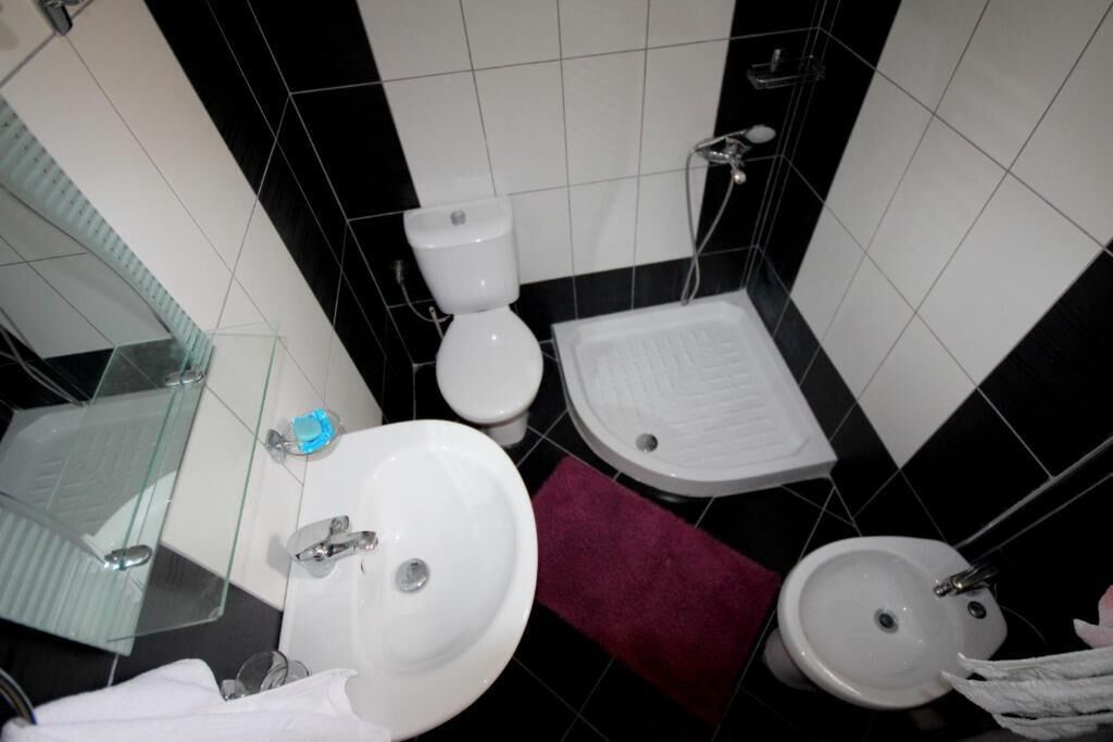 A bathroom with a toilet, sink, bidet, and glass shower enclosure.