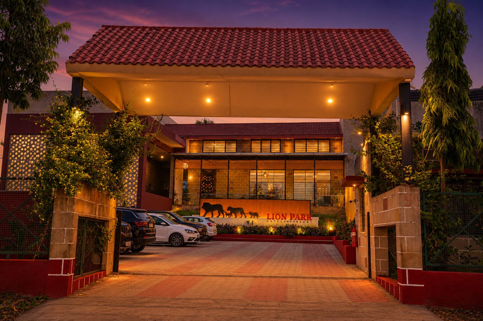 A hotel with a red-tiled roof, a central entrance with a lion statue, and a paved driveway.