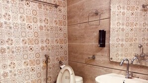 A bathroom with a toilet, sink, and mirror. - Hotel Metro Tower (New Delhi)