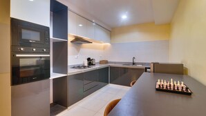 A modern kitchen with a built-in oven, microwave, and gas stove. There is a chessboard on the dining table. - 1-Bedroom Apartment in Lekki off Admiralty (Lekki Phase 1)
