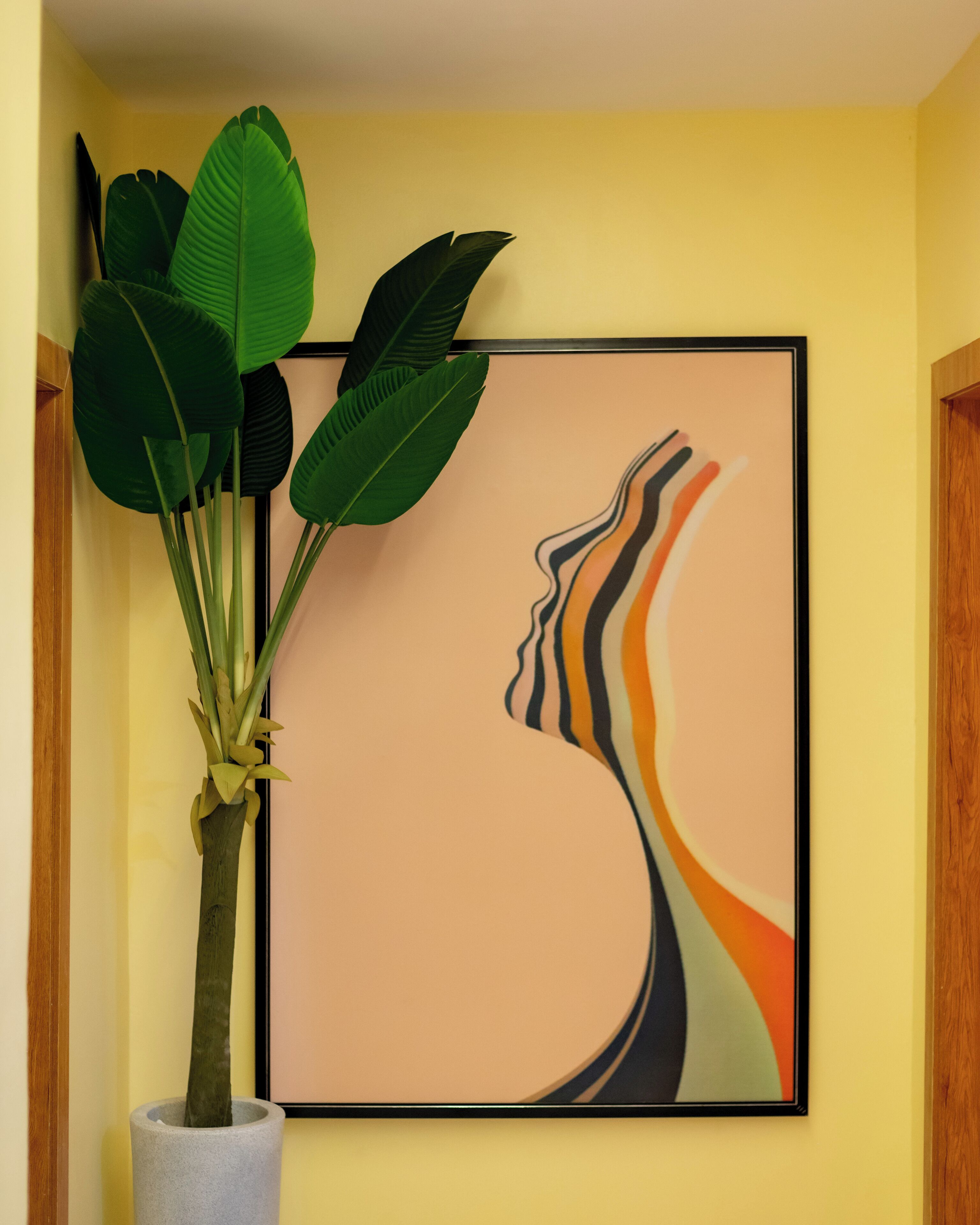 A framed abstract painting with a woman's profile on a yellow wall.