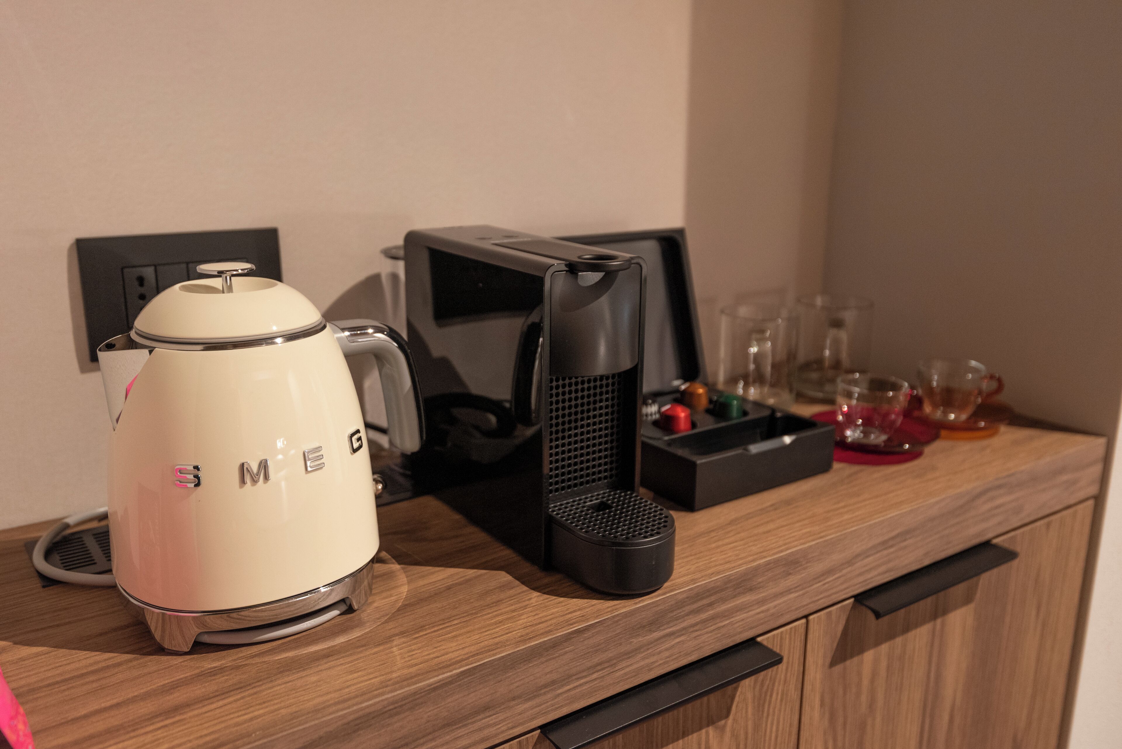 Une machine à café, un appareil à café noir et plusieurs verres sur un comptoir en bois.