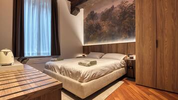 Una camera da letto con un letto, comodini, una scrivania e un quadro di grandi dimensioni appeso al muro.