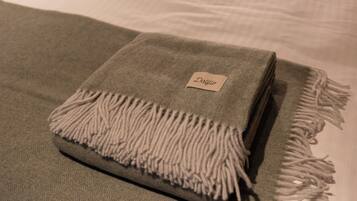 A neatly folded blanket with a label on it, placed on a bed.