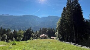 Paisaje montañoso con una casa en primer plano y cielo despejado.
