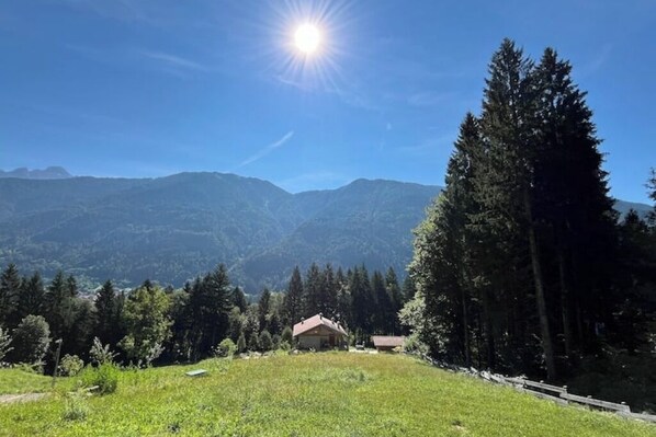 A mountain landscape with a house in the foreground and a clear sky.
