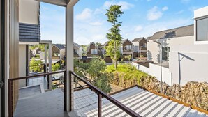 A residential building with a balcony, a view of neighboring houses, and a clear sky. - Dharma Villa by Kozystay - Jimbaran (Jimbaran)