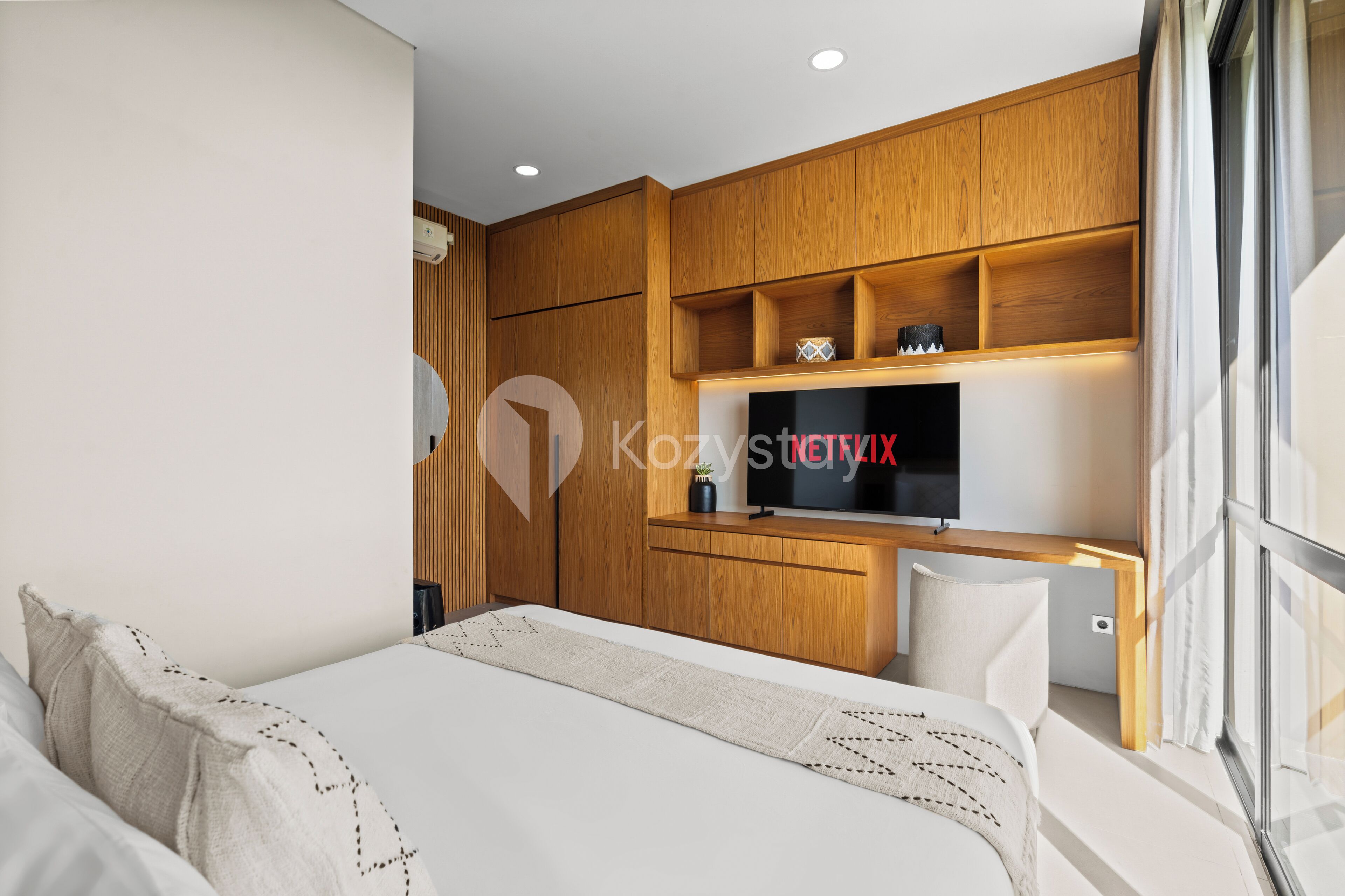 A modern bedroom with a bed, a desk, and a TV.