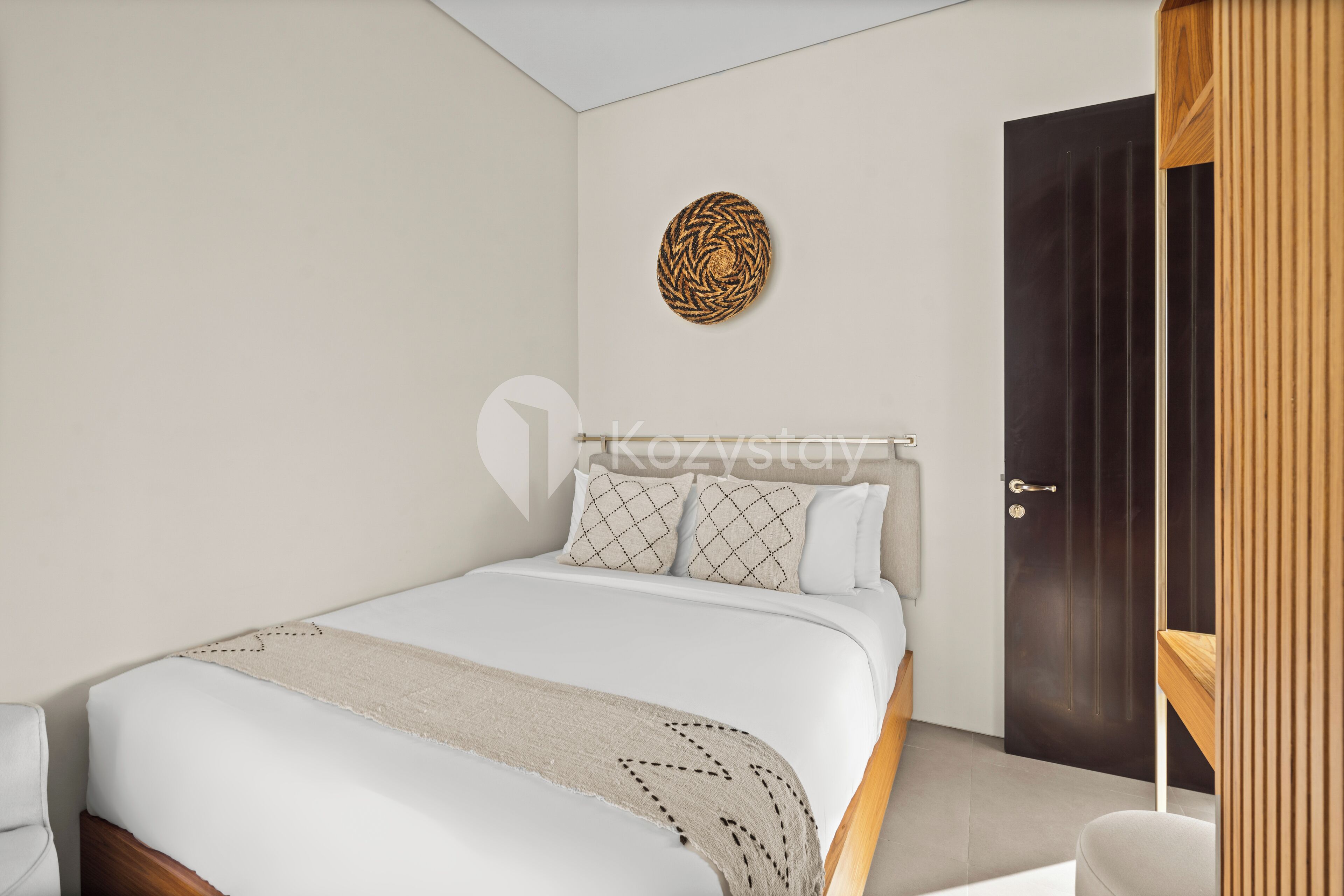 A bedroom with a bed, a bedside table, a door, and a wall decoration.