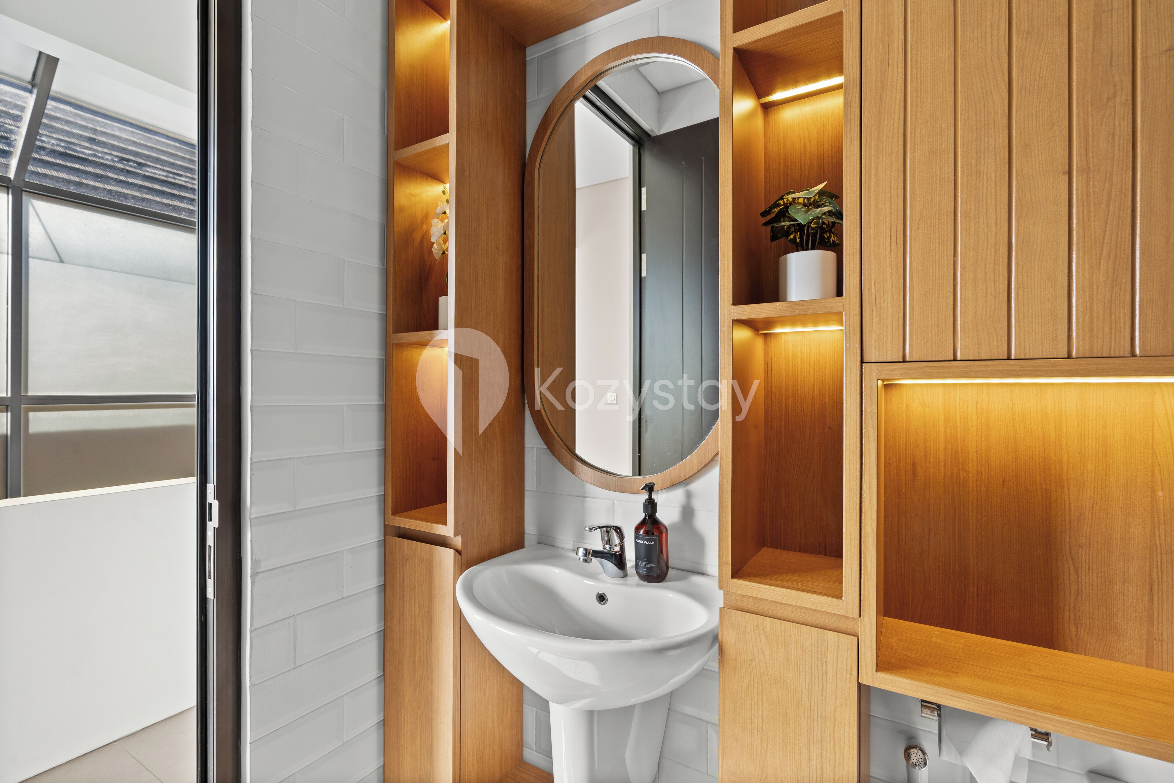 Een moderne badkamer met een wit wastafel, houten kastjes en een spiegel.