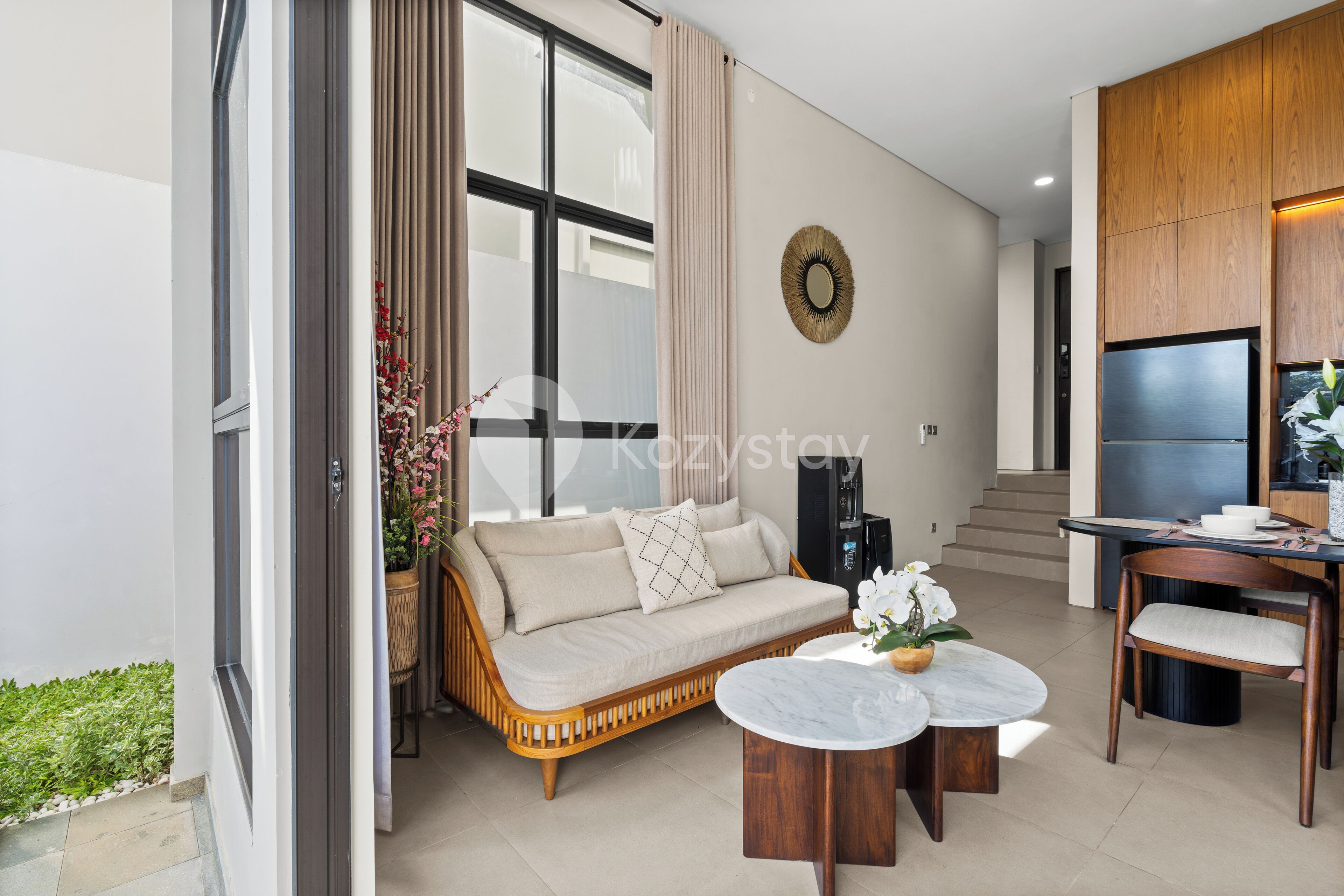 A modern living room with a sofa, two round tables, and a TV.
