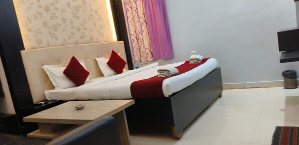 A hotel room with two beds, a small table, and a TV. - Hotel Shanti niketan by Nexottel (Deoghar)