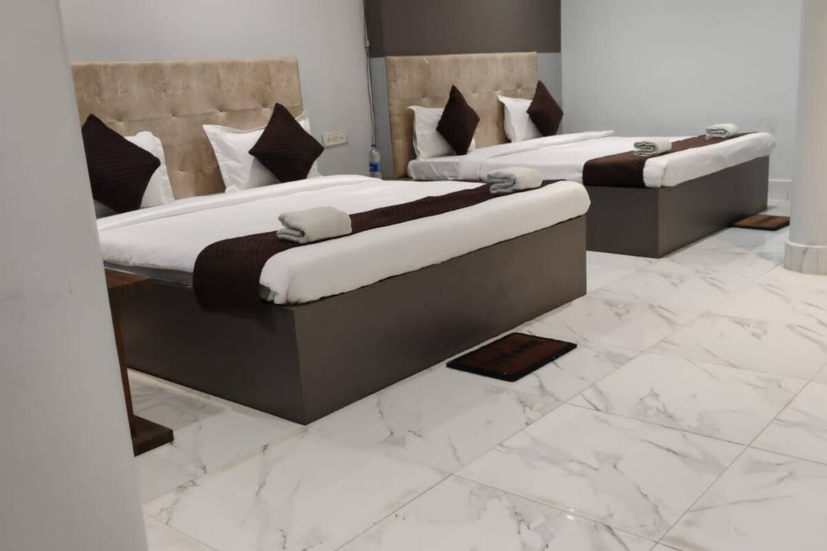 A hotel room with two beds, marble flooring, and a modern design.
