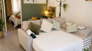 Une chambre à coucher comprenant un lit, un canapé, une table de chevet, un miroir et une porte donnant sur une salle de bain.