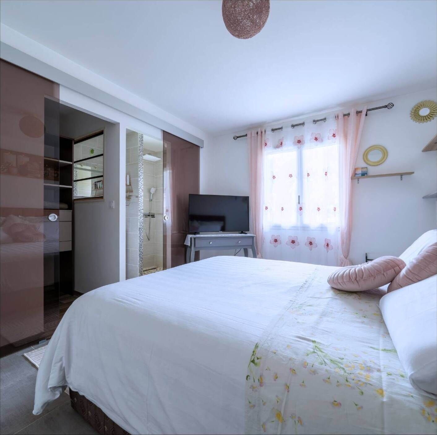 Ein Schlafzimmer mit Bett, Fernseher, Schreibtisch und Bad.