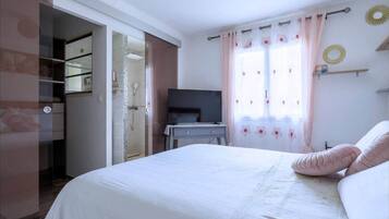 Ein Schlafzimmer mit Bett, Fernseher, Schreibtisch und Bad.