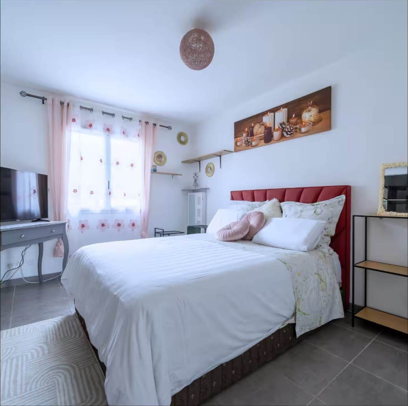 A bedroom with a bed, a TV, a desk, and a shelf.
