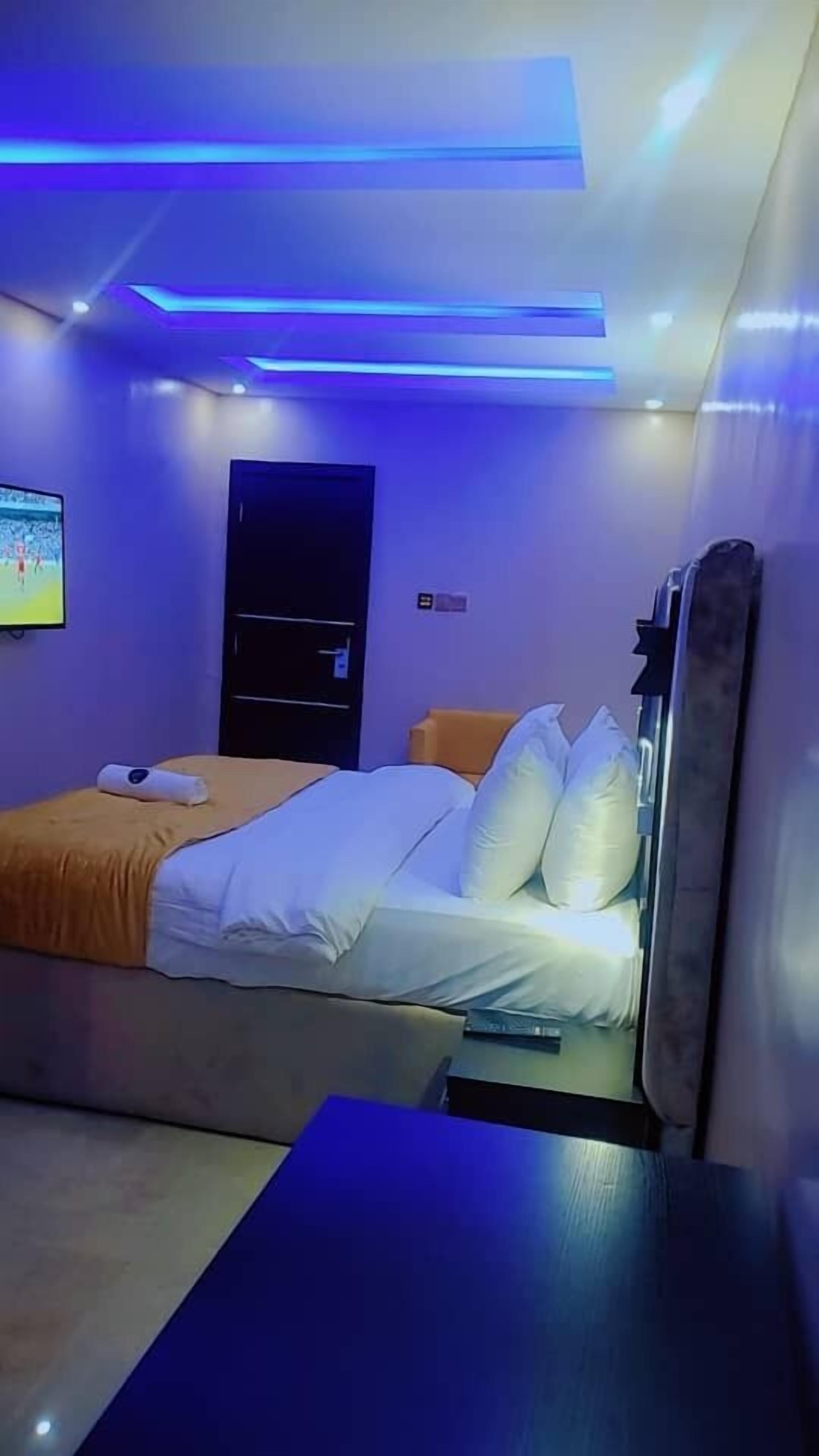 A modern bedroom with a bed, a TV, and a massage chair.
